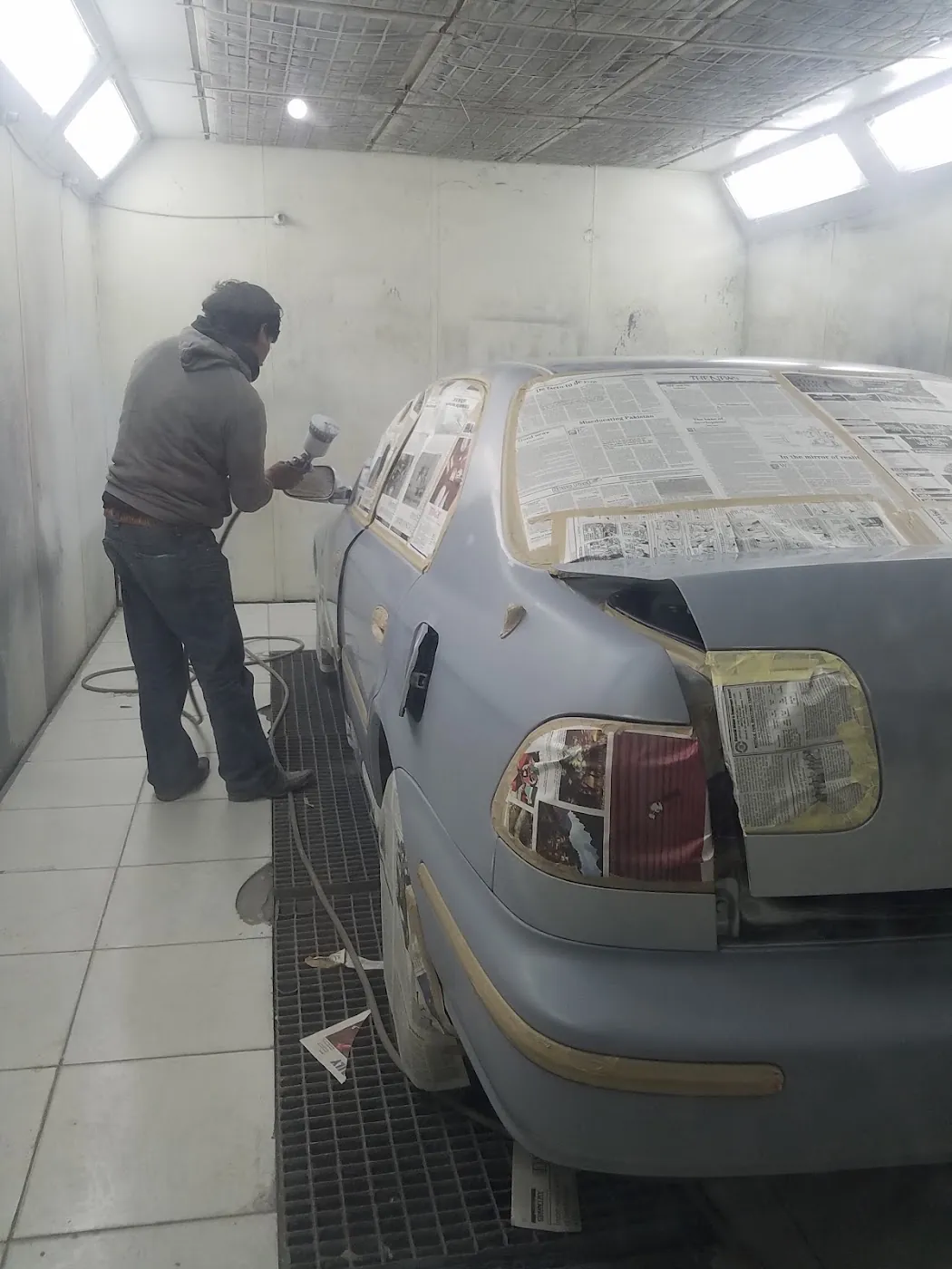 Our painter spraying a sedan inside the booth