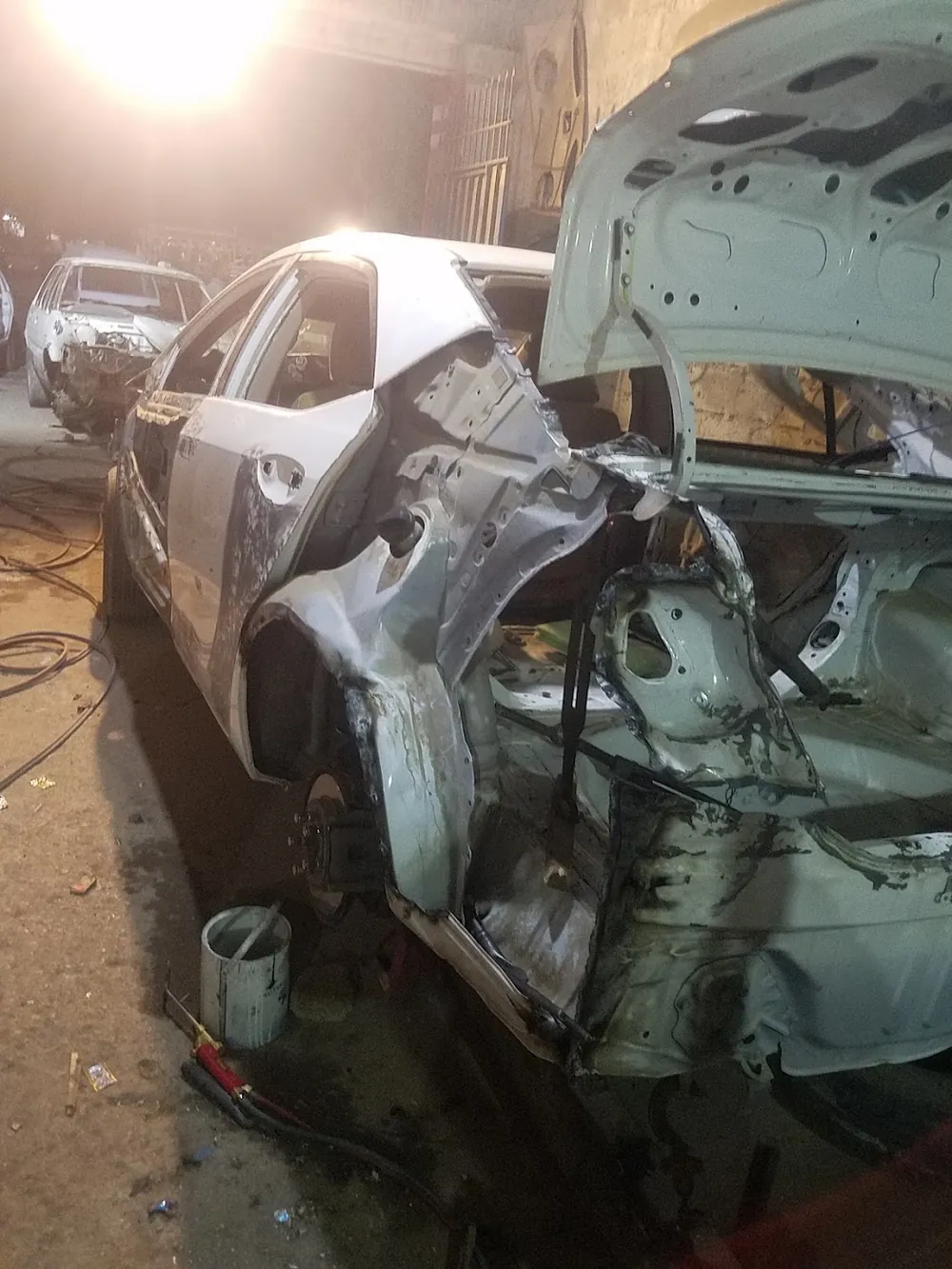 A rear-ended sedan stripped back to bare metal in our yard, ready for rebuilding